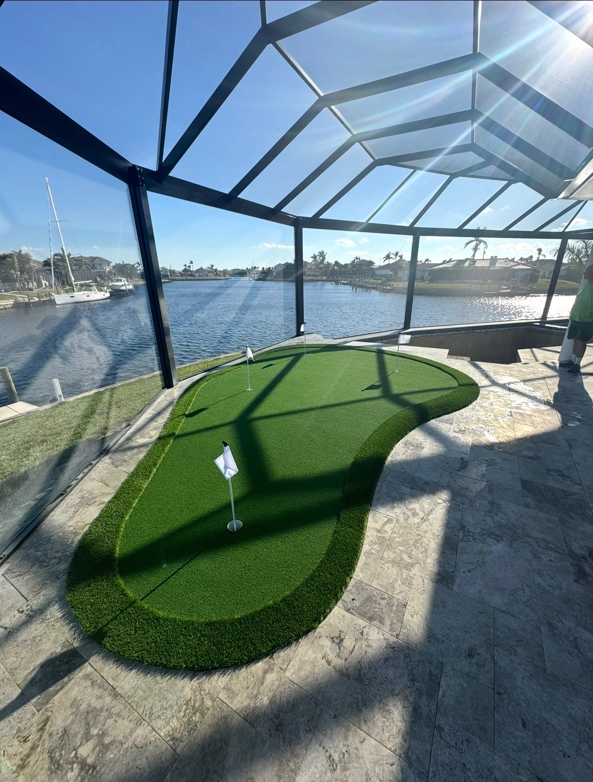 Artificial putting green beside a travertine pool deck