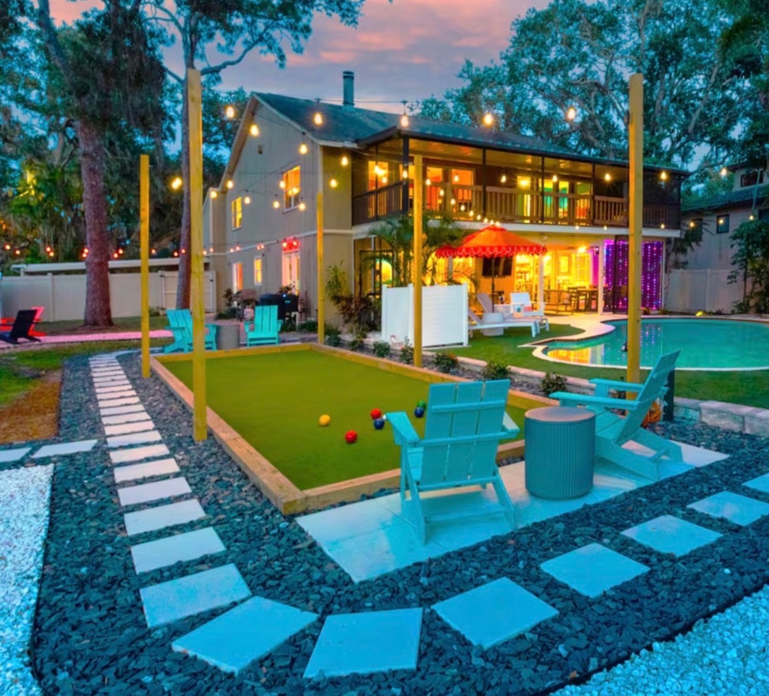Bocce court with paver walkway, turf and string lighting at dusk